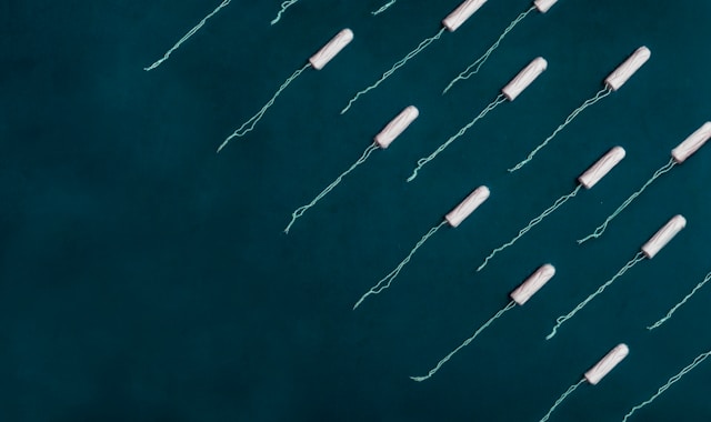 White tampons with blue strings on black background, Menstrual Equity for All Act.